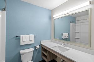 a bathroom with a toilet and a sink and a mirror at WoodSpring Suites Palm Springs - West Palm Beach in Palm Springs +21 photos