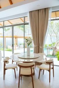 a dining room with a table and chairs at Anchan Flora Luxury 2BR Pool Villa in Thalang