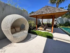 a wicker chair and a gazebo next to a pool at Anchan Flora Luxury 2BR Pool Villa in Thalang