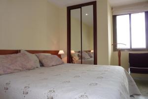 a bedroom with a large white bed with a mirror at La Nogalera 7 in Torremolinos