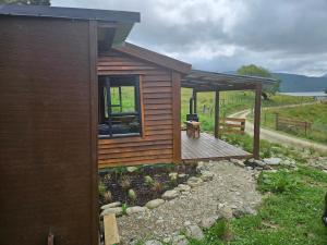 een kleine hut met een terras in een veld bij Mahakipaoa Cabin in Linkwater