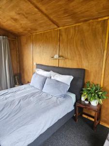 een bed in een kamer met een houten wand bij Mahakipaoa Cabin in Linkwater