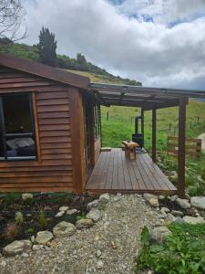 een hut met een houten terras met een bankje erop bij Mahakipaoa Cabin in Linkwater +2 foto's