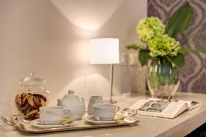 a table with a tray with cups and a vase of flowers at The Club Navona in Rome