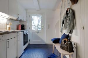 a kitchen with white cabinets and a chair in front of a door at Im Lütten in Braderup
