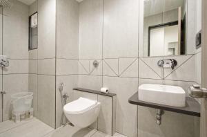 a bathroom with a toilet and a sink and a mirror at The Grand Platinum Hotel in Ahmedabad