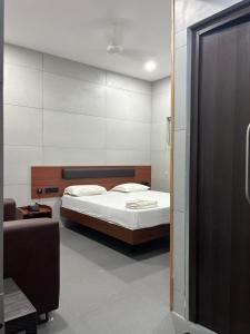 een slaapkamer met een bed en een bank erin bij Vijey Hotels in Tiruchchirāppalli