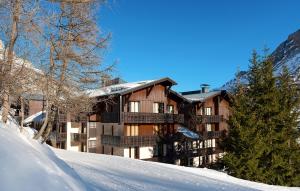 un edificio en una colina cubierta de nieve con árboles en Résidence Odalys Les Hauts du Rogoney, en Val dʼIsère
