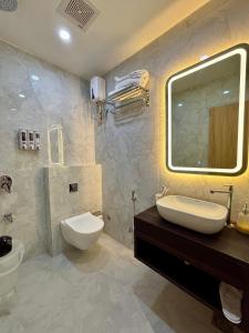 a bathroom with a sink and a toilet and a mirror at The Hyde Park Inn in Bilāspur