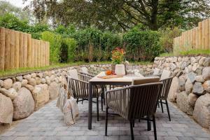 a table and chairs on a patio with a stone wall at Haus Möhre in Tinnum