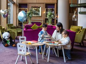 een vrouw en twee kinderen zitten aan tafels in een kamer bij Sofitel Strasbourg Grande Ile in Straatsburg