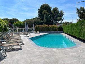 einen Pool mit Liegestühlen und Stühlen in der Unterkunft ibis Nîmes Ouest - A9 in Nîmes