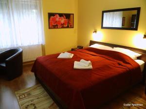 1 dormitorio con 1 cama roja y 2 toallas en Eszter Apartman, en Békéscsaba