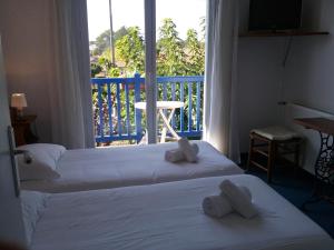 two beds in a hotel room with a balcony at Hôtel Land'Azur in Mimizan-Plage