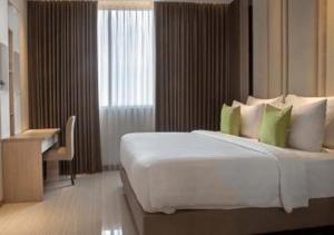 een slaapkamer met een groot wit bed en een bureau bij Hotel Dafam Pacific Caesar in Surabaya +195 foto's
