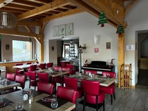 a restaurant with red chairs and tables and a piano at Hôtel du Centre - Restaurant Lelex'ir in Lélex