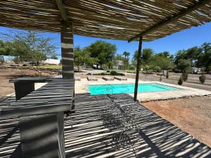 a patio with a bench and a swimming pool at White House Cottage in Koekoeb