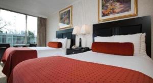 een hotelkamer met twee bedden en een groot raam bij El Tropicano Riverwalk in San Antonio