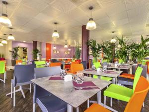 a dining room with tables and chairs and plants at ibis Styles Paris Roissy-CDG in Roissy-en-France