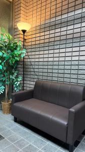 un divano marrone seduto davanti a un muro di 心斎橋難波関空直通 Ambers Hostel ad Osaka