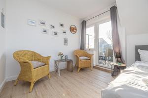 a bedroom with a bed and two chairs and a window at Seehof Boutique Appartements in Büsum