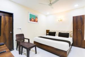 a bedroom with a bed and a chair in it at Hotel O Manglam Hotel in Chinhat