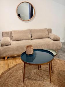 a living room with a couch and a table with a mirror at Charmant duplex in Moulins