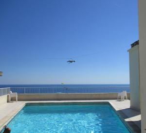 ein Schwimmbad mit dem Ozean im Hintergrund in der Unterkunft Royal Promenade in Nizza