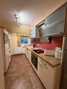 - une cuisine avec des appareils blancs et un mur rouge dans l'établissement Haus Sonnenschein, à Winterberg