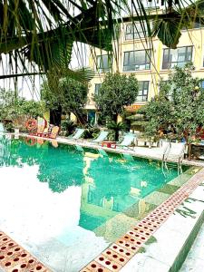 a swimming pool with chairs and a building at Lona Villa Tam Coc in Vũ Lâm