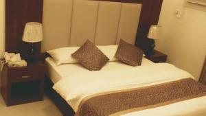 a bedroom with a bed with two lamps and a phone at Raha Suites in Dammam