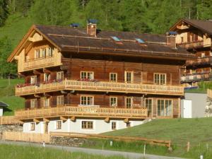 a large wooden house with a balcony on a hill at Alblerhof Unterstadl in Innervillgraten
