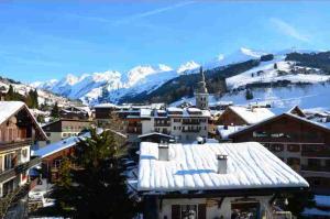 Un pueblo cubierto de nieve con montañas al fondo en Hotel Floralp, en La Clusaz