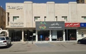 a large building with a flower authority sign in a parking lot at Taleen Serviced Apartments Al Nakheel in Riyadh