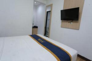 een slaapkamer met een bed en een tv aan de muur bij Kingstone Hotel in Kranggan-wetan Satu