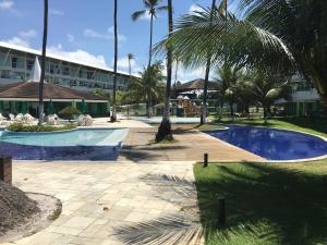un complejo con piscina con parque infantil y palmeras en Ancorar Flat Resort 2207 B en Porto De Galinhas