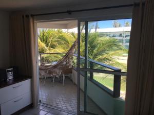 una puerta corredera de cristal que conduce a un patio con hamaca en Ancorar Flat Resort 2207 B en Porto De Galinhas