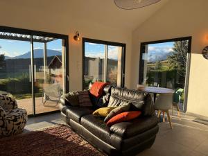 a living room with a leather couch and a table at The Eagle's Nest - cosy chalet for two in Jarjayes