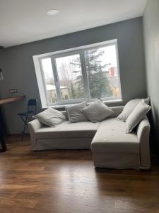 a couch in a living room with two windows at TK apartamenti 3 in Rēzekne