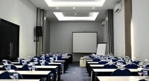 une salle de conférence avec des tables et des chaises et un écran blanc dans l'établissement G Suites Hotel By AMITHYA, à Surabaya 162 autres photos
