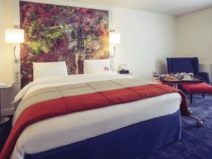 una camera da letto con un letto grande con un dipinto sul muro di Mercure Lille Marcq en Baroeul a Marcq-en-Baroeul Altre 67 foto