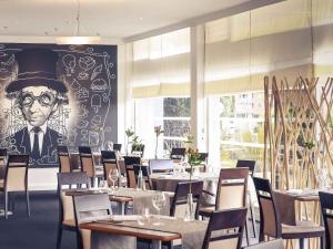 a restaurant with tables and a painting of a man in a top hat at Mercure Saint Lô Centre in Saint Lo