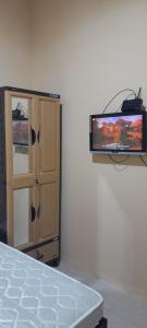 a tv sitting on a wall next to a bedroom at Arsya kost homestay in Balikpapan