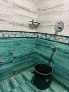 a bucket in a bathroom with green and white tiles at Jp Resorts in Muttupet