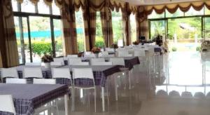 une salle de banquet avec des tables et des chaises blanches et des fenêtres dans l'établissement Lomdao Resort, à Ban Khao San