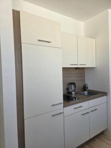 a white kitchen with white cabinets and a sink at Hotelappartements BR in Fürth +6 photos