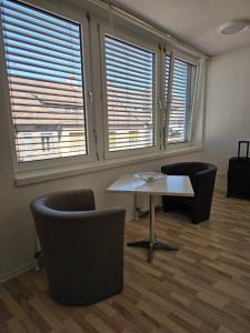 een kamer met een tafel, 2 stoelen en ramen bij Hotelappartements BR in Fürth +6 foto's