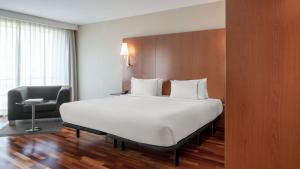 a bedroom with a large white bed and a chair at AC Hotel La Rioja by Marriott in Logroño