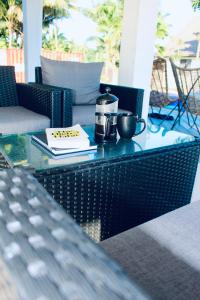 a glass table with two coffee cups and a book at Villa Ahava in Pacific Harbour