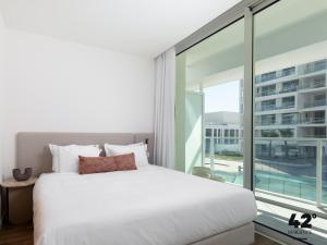 een slaapkamer met een wit bed en een groot raam bij 42 Residence by Brown in Eilat